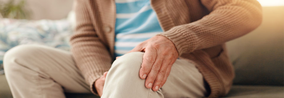 Mann hält sich schmerzhaft das Knie – Symbolbild für Fibromyalgiesyndrom.